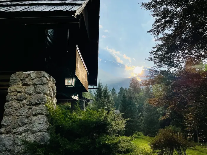 Red Beech Cabin's stone pillar and wrought-iron lantern at dusk, forest and evening sky beyond