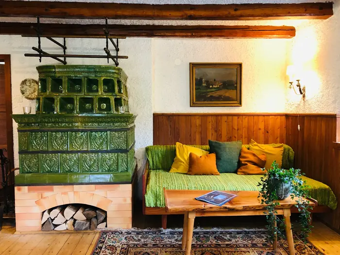 Close-up of the original green krušna peč (tiled wood-burning stove) beside the living-room sofa