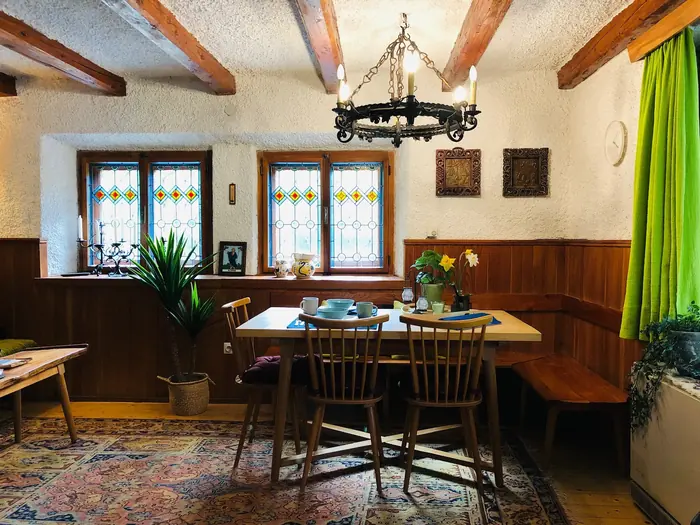 Stained-glass window detail above the dining table, with fresh flowers and green curtains