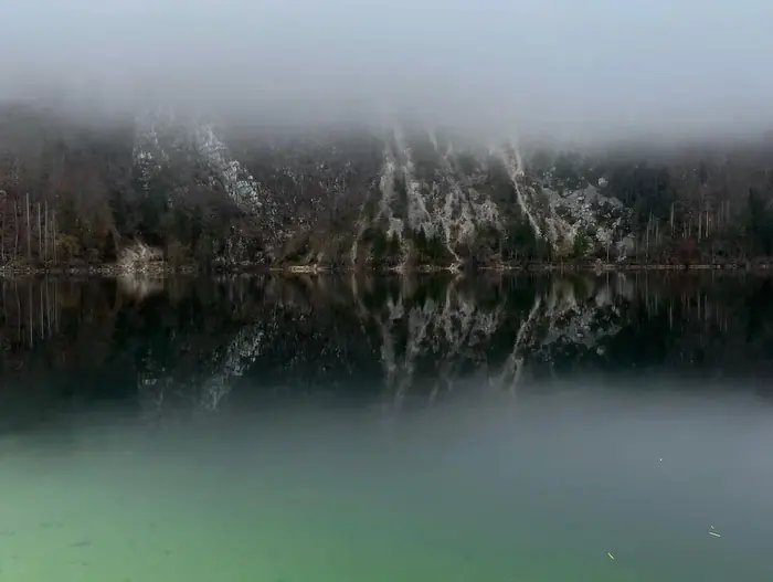 Misty autumn reflection of the mountains in Lake Bohinj
